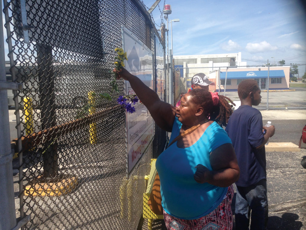 Zalaka Thompson attaching a flower to the fence at PES refinery.